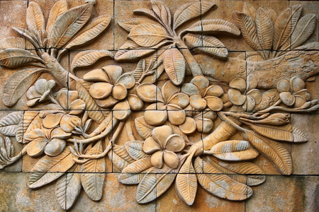Low relief cement Thai style handcraft of plumeria or frangipani flowers  on wallの写真素材
