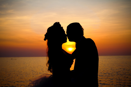 Love couple kissing romantic scene silhouette at sunset.の写真素材