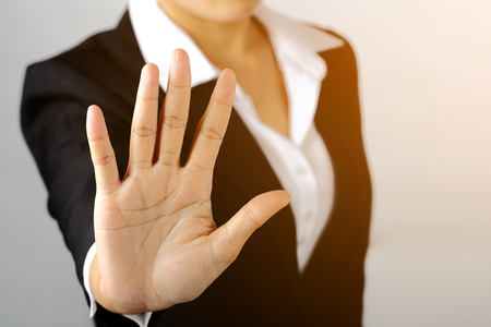 Prohibition symbol. Serious business woman shows stop sign talk to hand gesture on gray blackground.の写真素材
