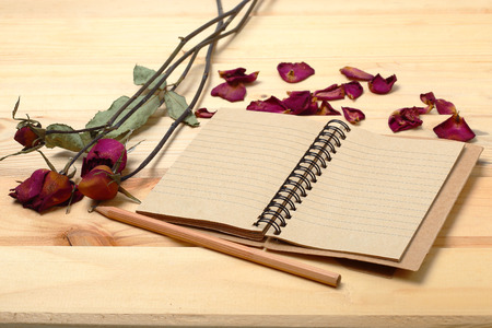 Empty notebook and dry roses with pencil on old wood, eco concept background for valentine.の写真素材