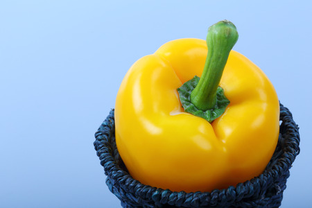 Close up of sweet yellow bell pepper isolated in basket on blue background.の写真素材