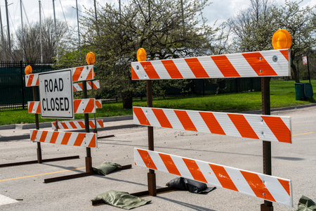 Side view of a â€˜Road Closedâ€™ sign with orange barriers in the USA, showing urban safety measures, restricted roadway, and accessible pathways