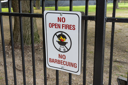 White fence sign stating â€˜No Open Fire, No Barbecueâ€™, emphasizing park safety rules, fire prevention, and responsible outdoor use