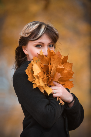 the beautiful girl with a bouquet of autumn leavesの写真素材