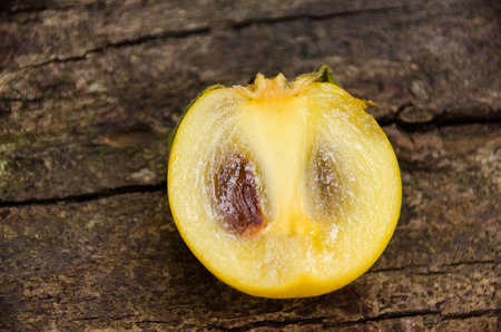 Fruit in the persimmons family in Thailand. Persimmon cut  half on top of natural wood.の写真素材