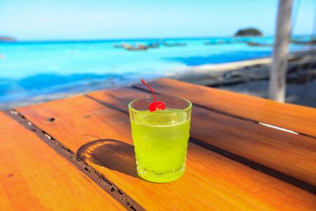 Glass of green drink is on the beach table with sofe sunrise in afternoon, Cocktail, Mocktail, cold drink Served on the beach, Koh Lipe, Satun, Thailandの写真素材