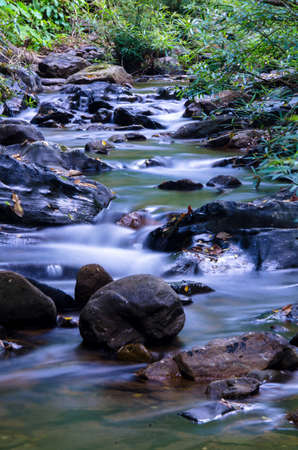 Small waterfalls streaming into small pond in green forestÂ in long exposure, Thailandの写真素材