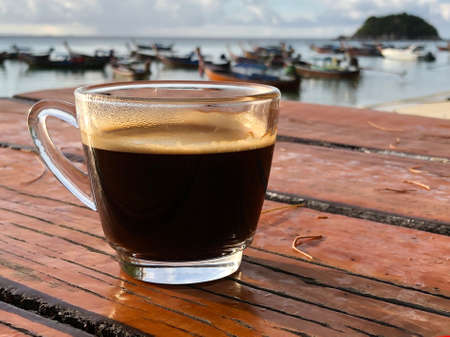 Black coffee on the wooden table, beachside , nature light. Thailandの写真素材
