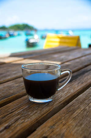 Black coffee on the beachside table with seascape background, nature light. Thailandの写真素材