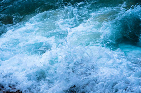 Water splashing. Crystal clear sea water beating against the rocks and cliffs. Waves and sea foam.