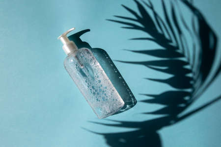 Foamy micellar water on a blue background with a shadow from a palm tree