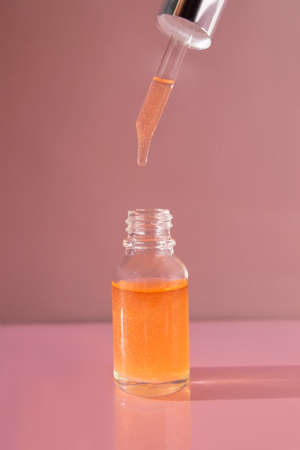 A bottle of nail oil with a dropper on a pink background. Front view.の写真素材