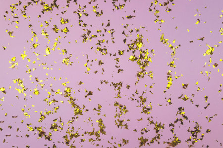 Golden glittering confetti on a pink backgroung. Festive backgroungの写真素材