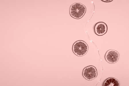 Glowing garland and oranges in a pink shade on a pink background. Place for text.の写真素材