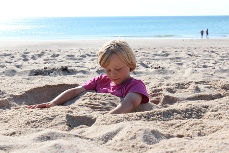 child sitting buried in the sandのeditorial素材