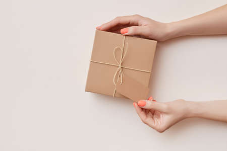 Mock up of brown craft present box in womens hands on the biege backgroundの写真素材