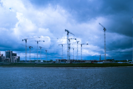 A lot of construction cranes on background of stormy sky.の写真素材