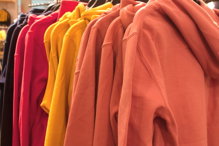 Hanger with colorful hooded sweaters in clothing storeの写真素材