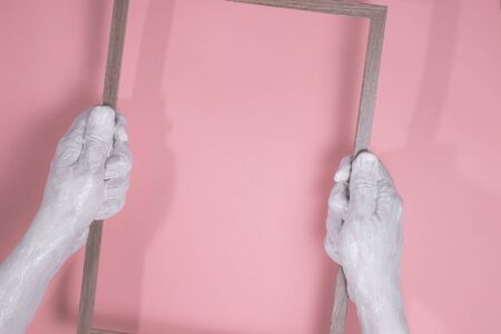 hands in the paint to keep the frame for the inscription on pink backgroundの写真素材
