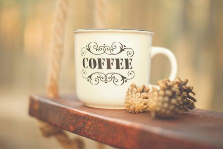a large Cup labeled coffee stands on a wooden swingの写真素材