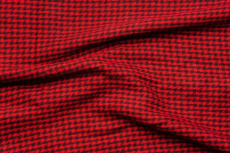 Wool cloth with folds in small black cage on a red background