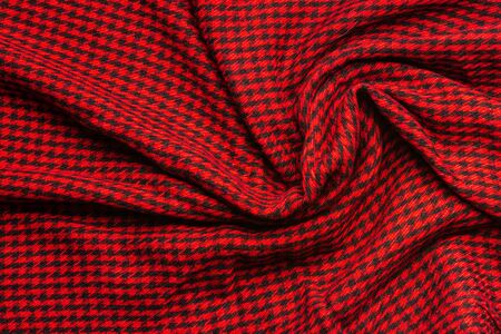Wool crumpled cloth in a small black cage on red background