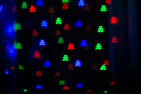 Beautiful bokeh in the form of bears of different colors on dark background