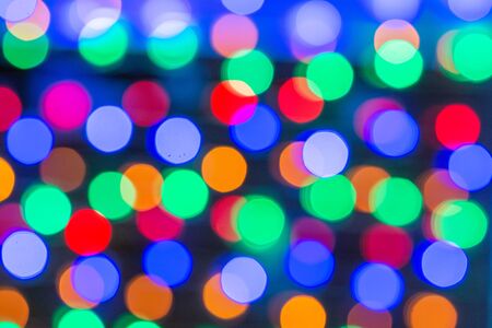 Beautiful bokeh in the form of medium-sized multicolored circles against dark backgroundの写真素材