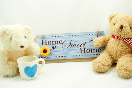 Home sweet home label with brown and white teddy bear and blue heart cup on white backgroundの写真素材