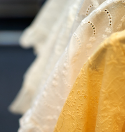 Yellow cloth with thai design with blurry white cloth in backgroundの写真素材