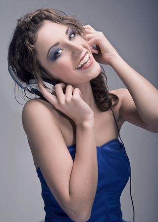 Young beauty listening to the music - gray backgroundの写真素材