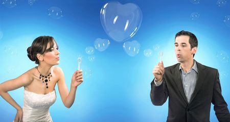 Wedding couple blowing heart shaped romantic soap bubblesの写真素材