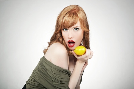 Young red hair woman holding a lemon の写真素材