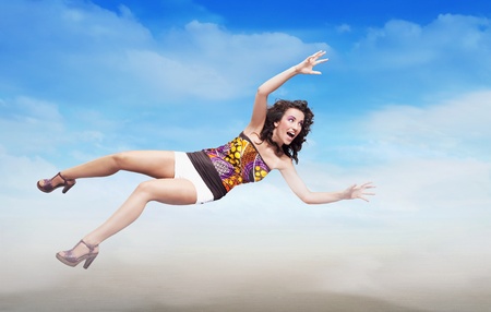 Young brunette beauty jumping over sky background, lots of copy-spaceの写真素材
