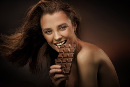 Cheerful woman eating chocolateの写真素材