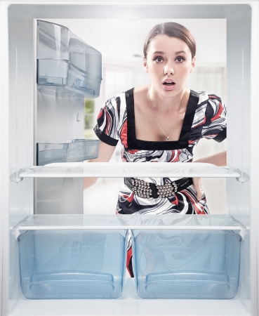 Young woman looking on empty shelf in fridge.の写真素材