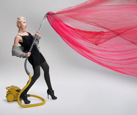 Young woman using vacuum cleaner. Isolated.の写真素材