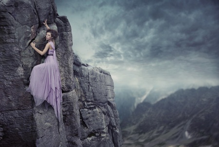 Conceptual photo of a woman climbing to the top of a mountainの写真素材