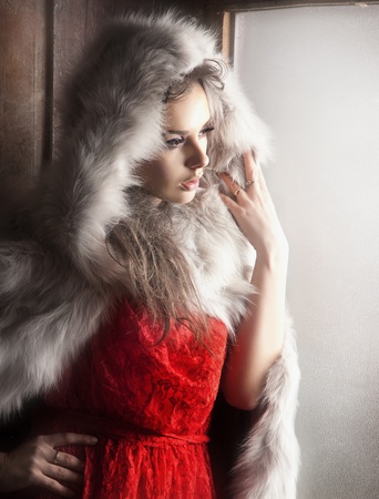 Sexy woman as a red hood looking out windowの写真素材