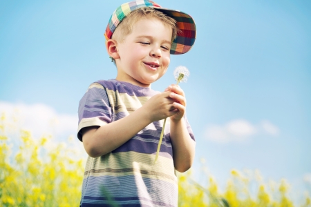 Laughing kid carrying blow-ball in his handsの写真素材