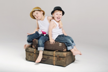 Two small cute brothers sitting on the suitcasesの写真素材
