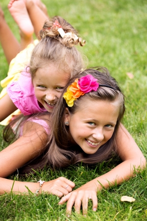 Two smiling girls playing on the summer green grassの写真素材