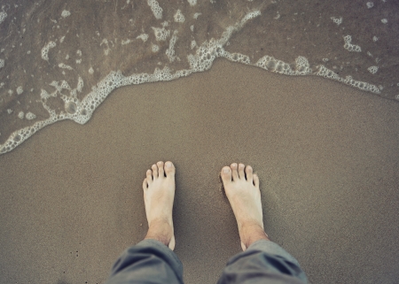 Photo of male bare foot near the sea waterの写真素材