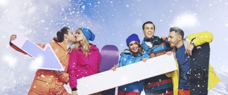 Laughing group of young snowboarders with the snowing background