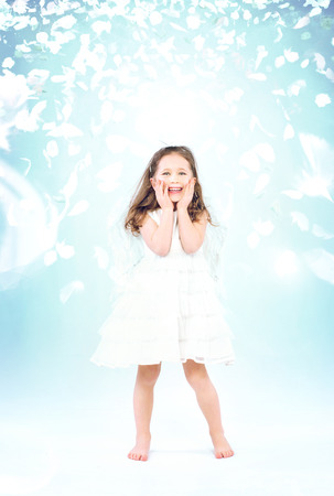 Cute little girl among flying rose petalsの写真素材