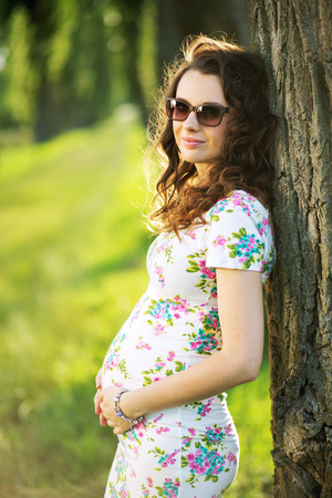 Marvelous pregnant mom leaning against the treeの写真素材