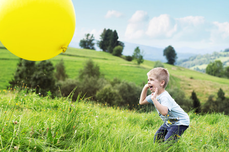 Joyful boy bouncing a yellow balloonの写真素材