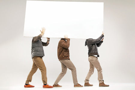 Conceptual picture of three guys carrying the empty boardの写真素材