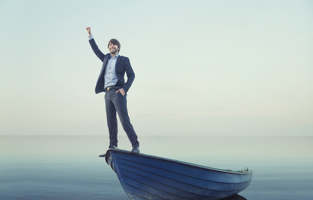 Cheerful young guy on the tiny boatの写真素材