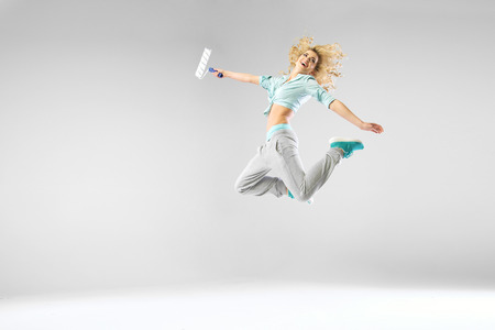 Woman jumping and holding a paintrollerの写真素材